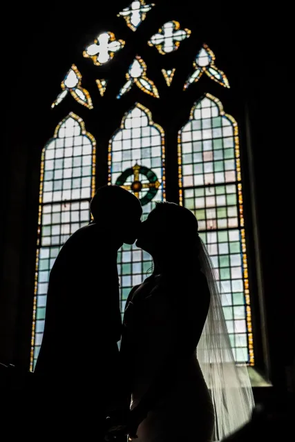 Silhouette of newlyweds in front of a stained-glass window at St Joseph's Catholic Church in Sydney.